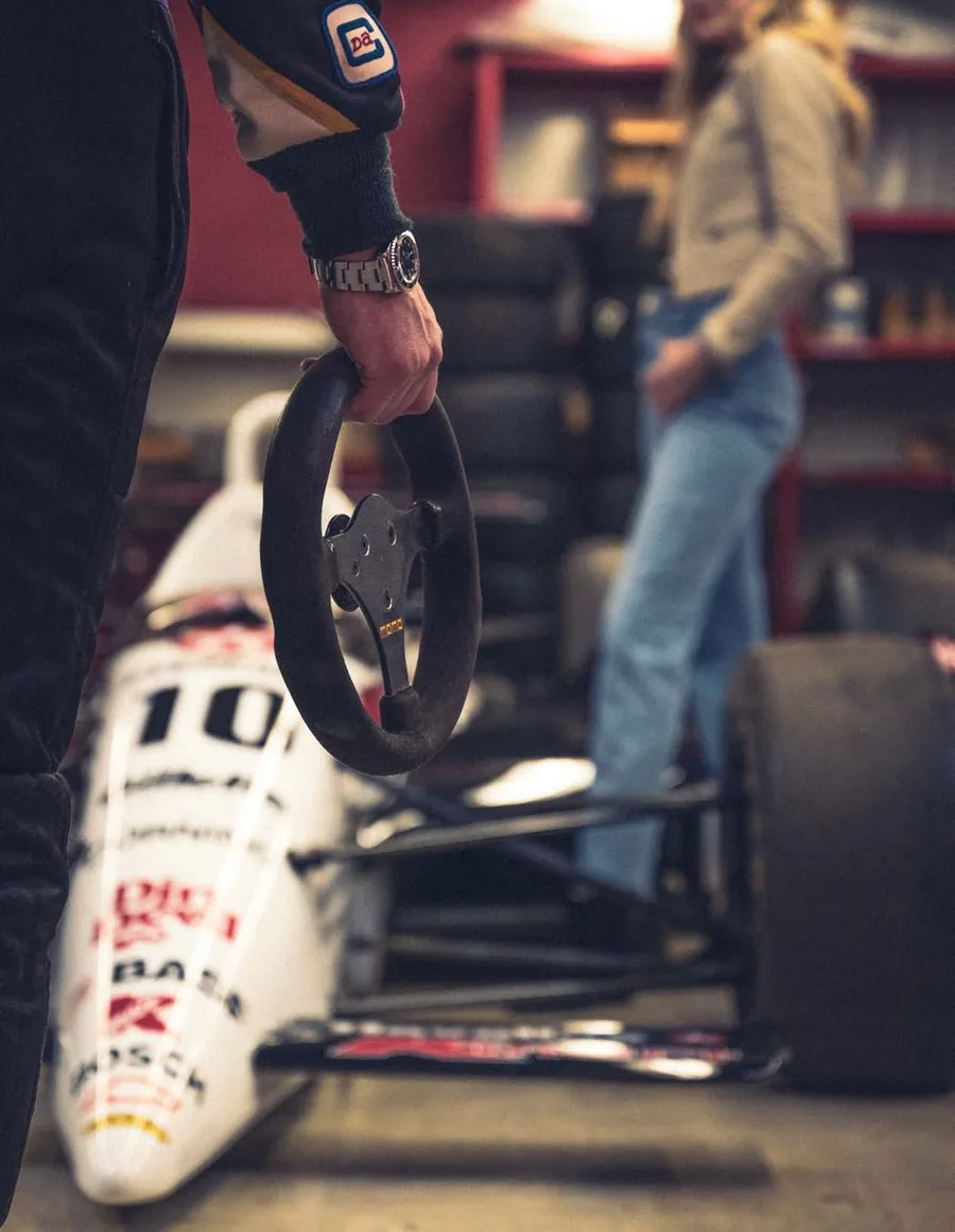 A mechanic carrying a steering wheel through a race workshop